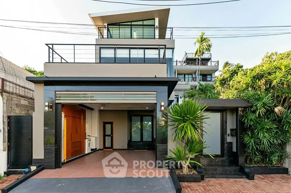 Modern multi-story house with sleek design and lush greenery in urban setting.