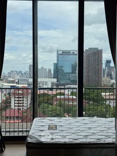 Stunning cityscape view from a high-rise apartment window with a cozy interior setting.