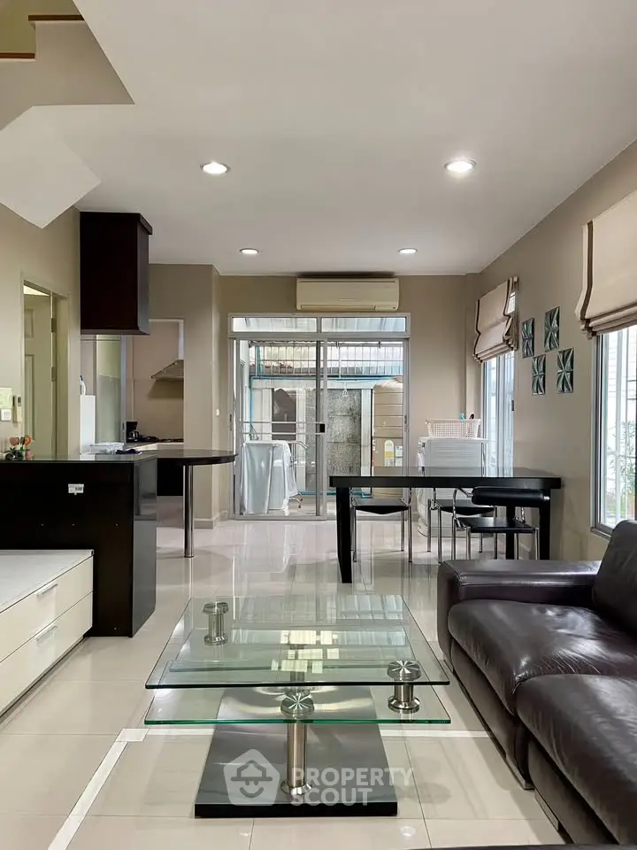 Spacious modern living room with glass coffee table and open kitchen layout