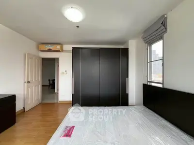 Spacious bedroom with modern wardrobe and large window offering city views.