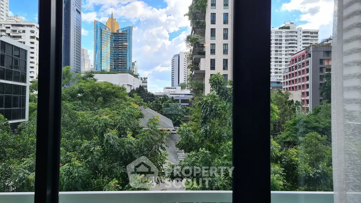 Stunning urban view from a high-rise window showcasing lush greenery and modern architecture.