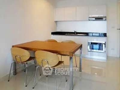 Modern kitchen with sleek white cabinets and dining area in contemporary apartment.