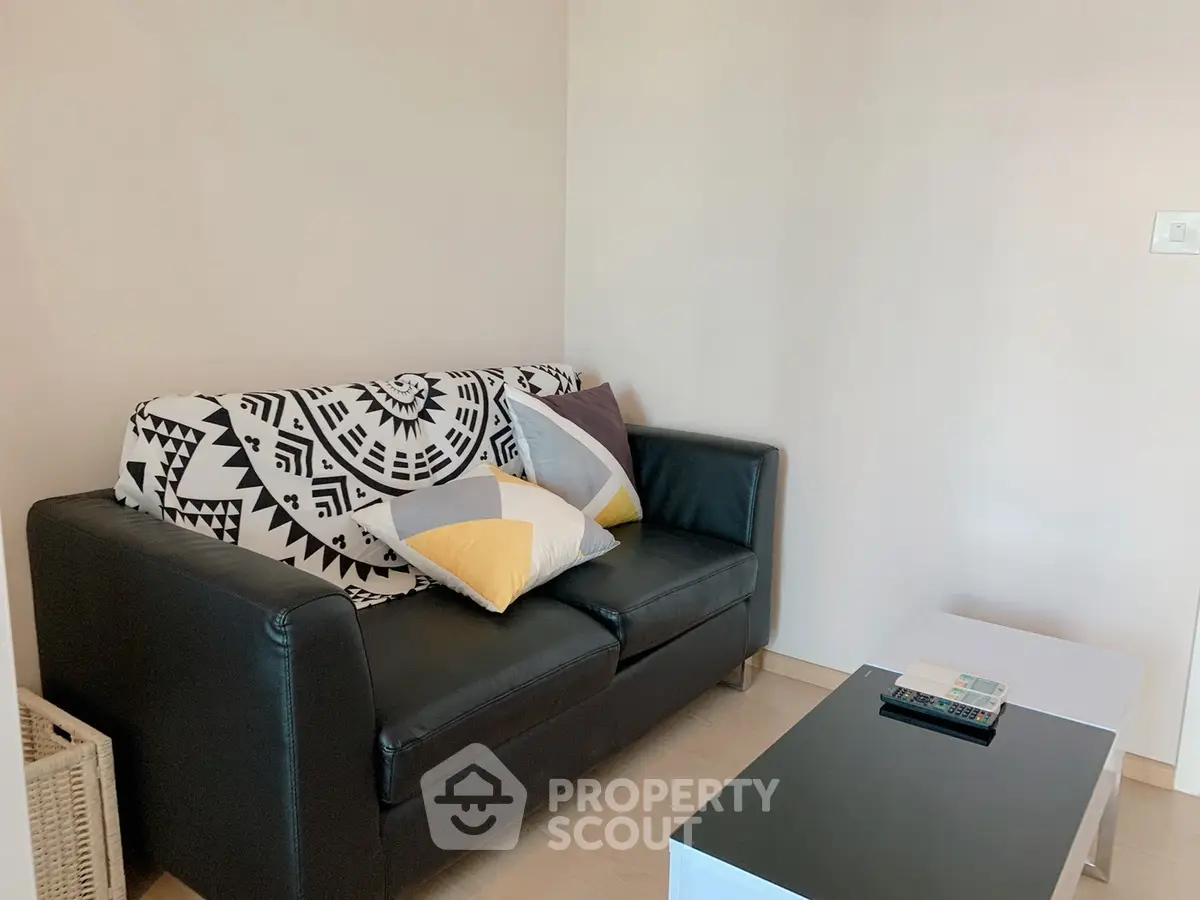 Cozy living room with stylish black sofa and modern coffee table, perfect for relaxation.