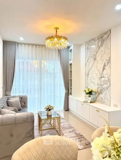 Elegant living room with plush sofa, marble accent wall, and chandelier lighting.