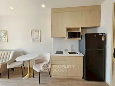 Modern kitchen with sleek cabinetry, compact dining area, and integrated appliances in a stylish apartment.