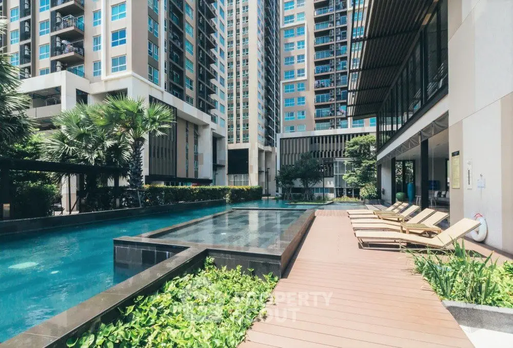 Luxurious condominium pool area with sun loungers and modern architecture.