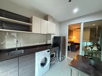 Modern kitchen with washing machine and sleek cabinetry adjacent to cozy living room.