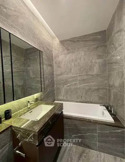 Luxurious modern bathroom with elegant marble tiles and built-in bathtub, perfect for relaxation.
