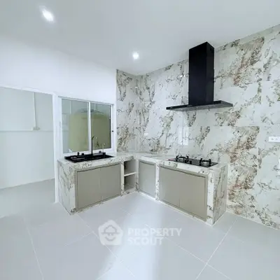 Modern kitchen with marble backsplash and gas stove in a spacious open layout.