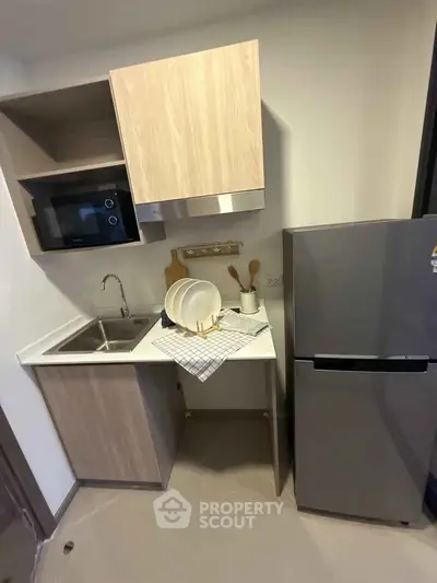 Modern compact kitchen with sleek cabinetry, stainless steel sink, and fridge, perfect for urban living.