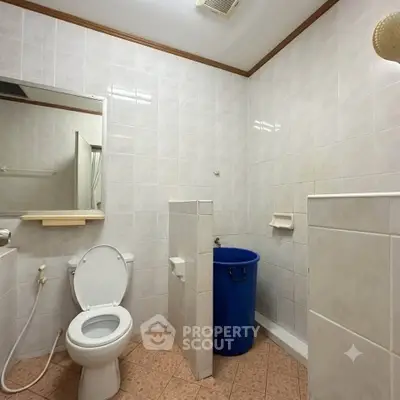 Spacious bathroom with tiled walls, modern fixtures, and a blue laundry bin.