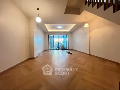 Spacious living room with elegant wooden flooring and modern lighting, perfect for family gatherings.