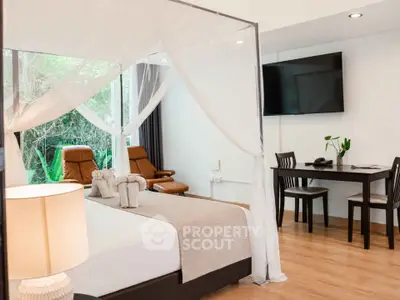Luxurious bedroom with canopy bed and modern decor, featuring a wall-mounted TV and elegant seating area.