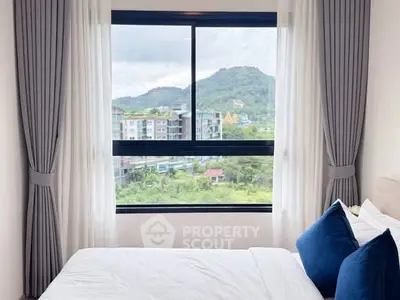 Cozy bedroom with scenic mountain view through large window, featuring elegant curtains and plush pillows.