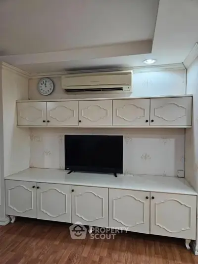 Charming living room with built-in cabinets, air conditioning, and a sleek TV setup.