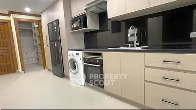 Modern kitchen with sleek cabinetry, built-in oven, and washing machine in a stylish apartment.