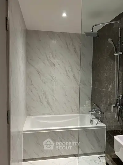Modern bathroom with elegant marble tiles and a sleek glass shower enclosure.