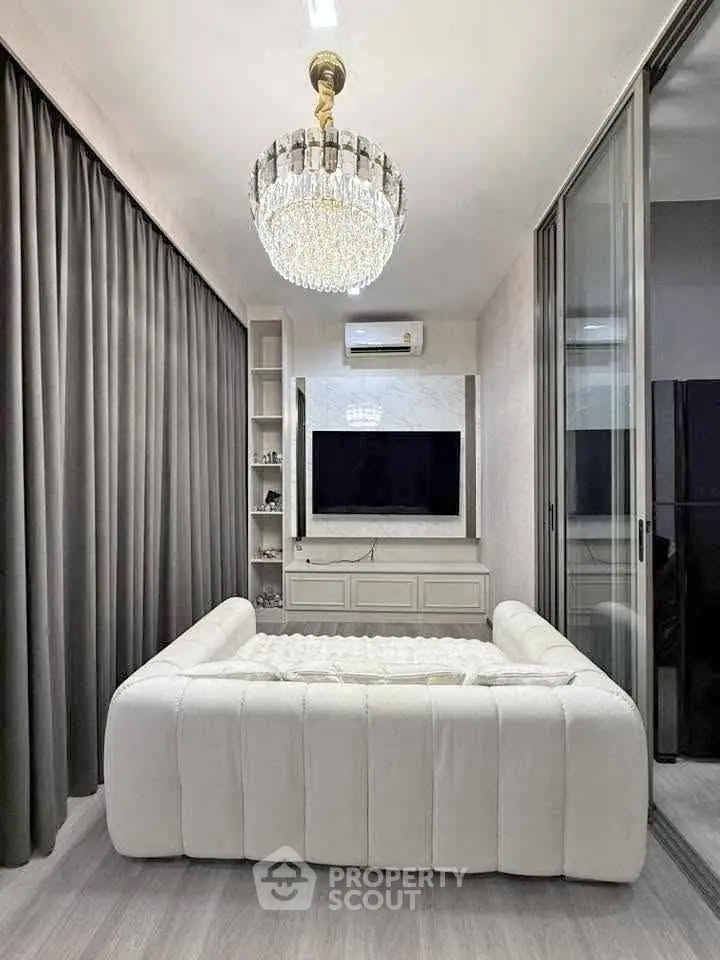 Luxurious modern living room with elegant chandelier and plush white sofa, perfect for relaxation.