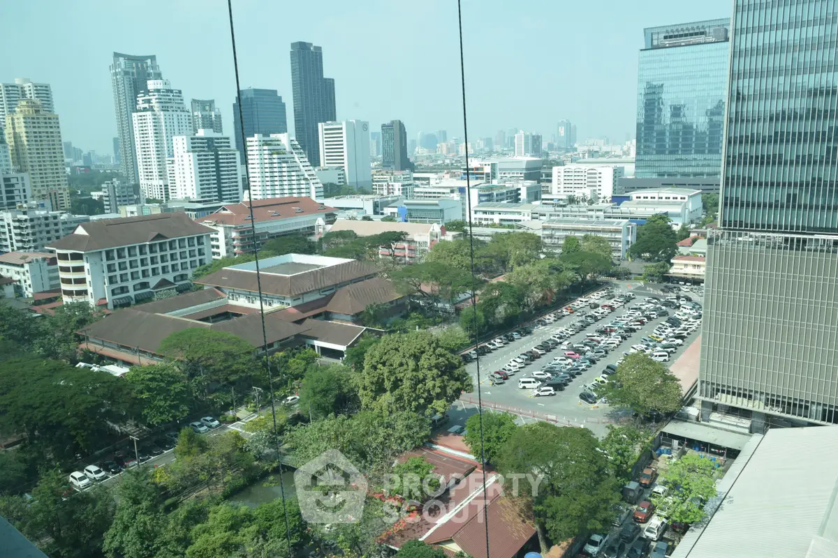 Stunning cityscape view from high-rise building with lush greenery and urban skyline.