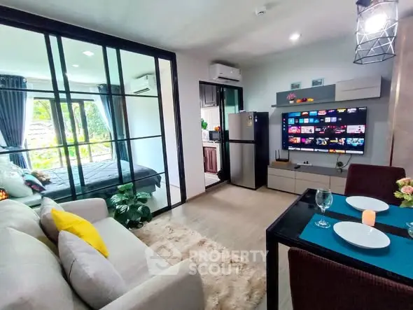 Modern open-plan living room with glass partition, cozy decor, and smart TV setup in stylish apartment.
