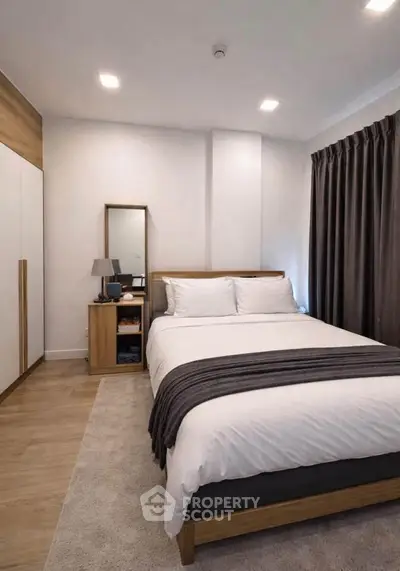 Modern bedroom with cozy decor and wooden furniture, featuring a comfortable bed and stylish lighting.