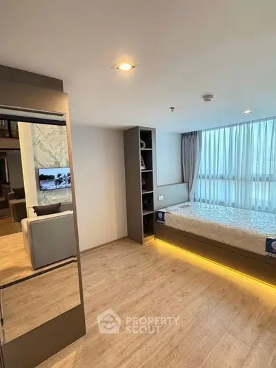 Modern bedroom with built-in storage and large window in a stylish apartment.