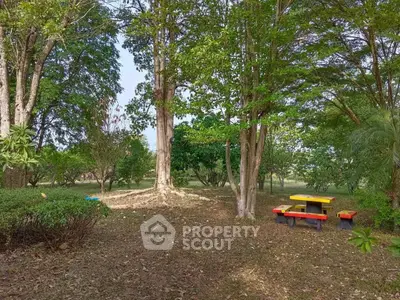 Serene garden area with colorful picnic table surrounded by lush trees, perfect for relaxation and outdoor activities.