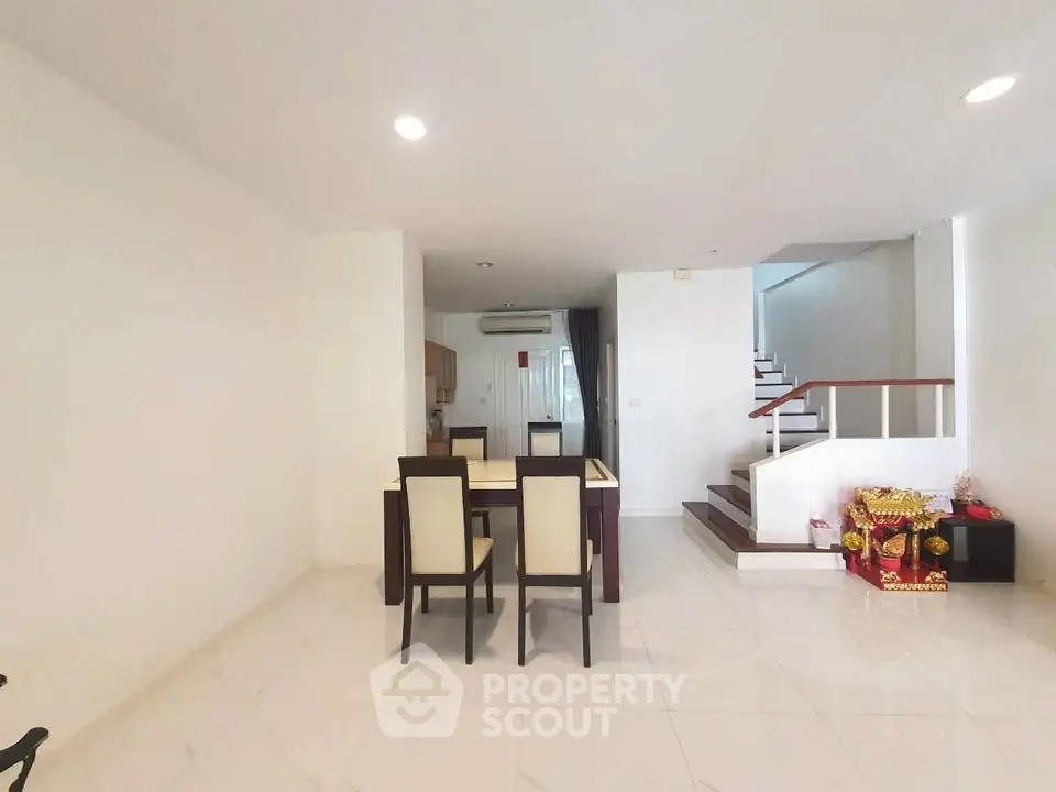 Spacious modern living area with dining set and staircase in a bright open layout