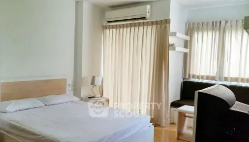 Spacious bedroom with natural light and modern furnishings in a cozy apartment.