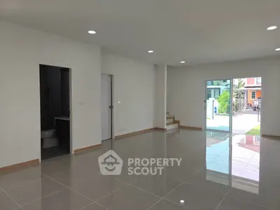 Spacious modern living room with glossy tiles and large windows overlooking garden