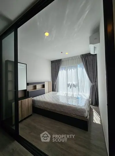 Modern bedroom with large window and stylish furnishings in a contemporary apartment.