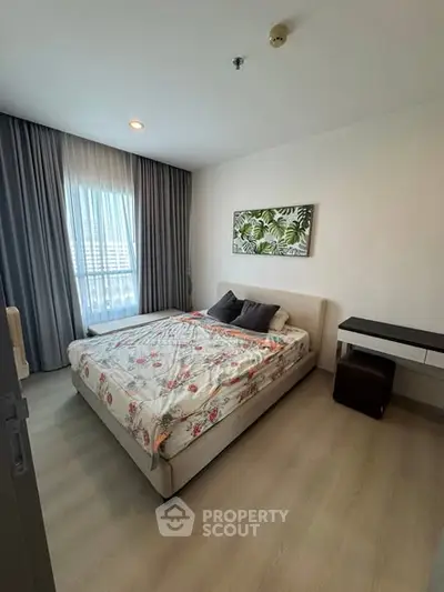 Cozy bedroom with modern decor and large window offering natural light.