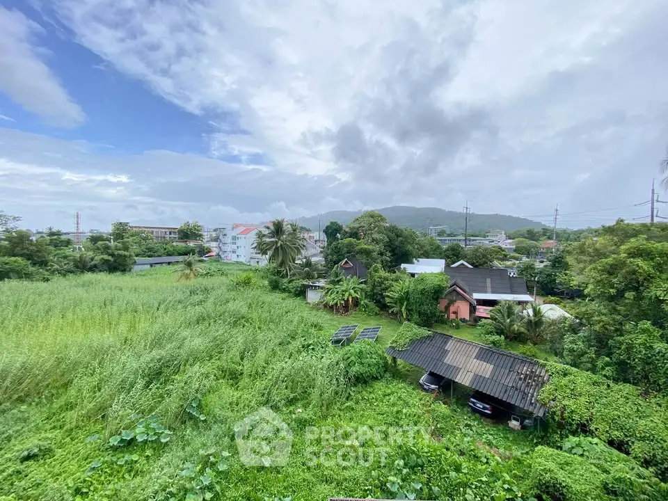 Scenic view of lush green landscape with residential buildings in the background.