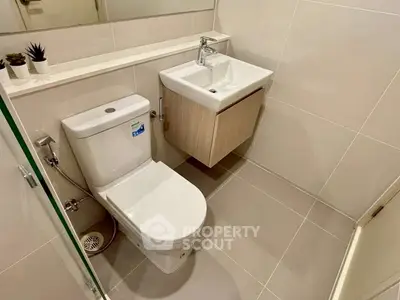 Modern bathroom with sleek fixtures and minimalist design, featuring a compact sink and toilet.