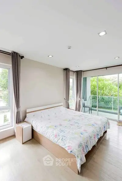 Spacious bedroom with large windows and balcony access in modern apartment