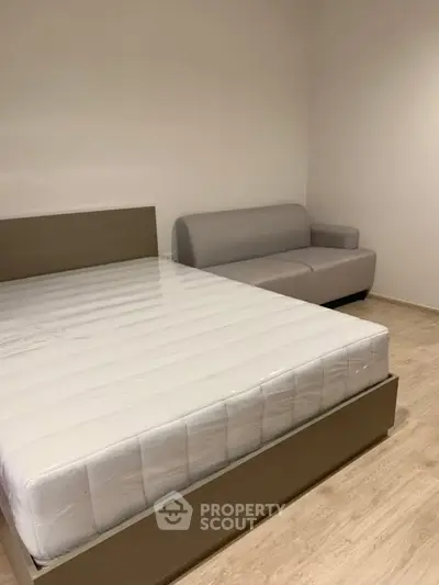 Modern bedroom with minimalist design featuring a bed and a cozy sofa, perfect for relaxation.