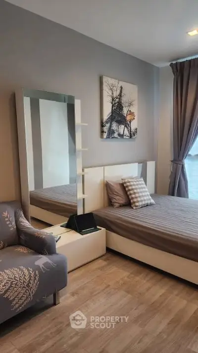 Modern bedroom with stylish decor and large mirror, featuring cozy bed and elegant armchair.