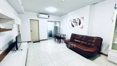 Spacious living room with modern decor and air conditioning, featuring a cozy brown sofa and dining area.