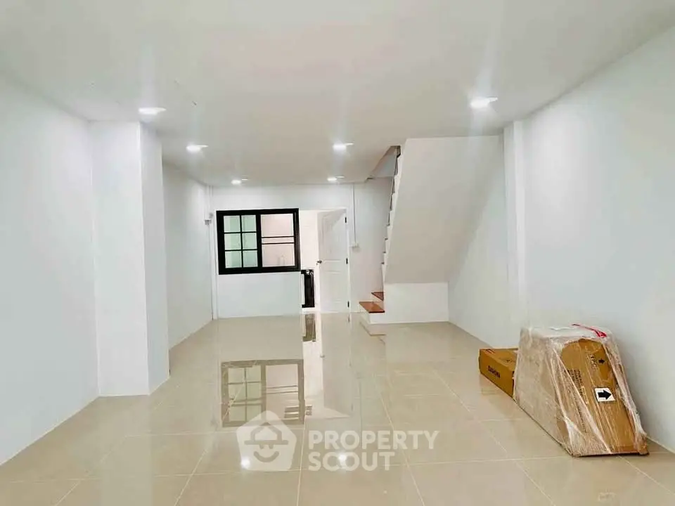 Spacious modern living room with glossy tiled floors and staircase