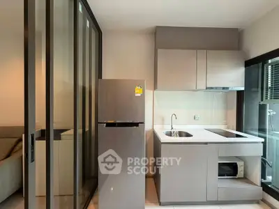 Modern compact kitchen with sleek cabinetry and glass partition in stylish apartment.