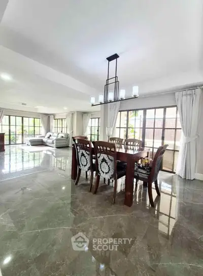 Spacious open-plan living and dining area with elegant furnishings and large windows.