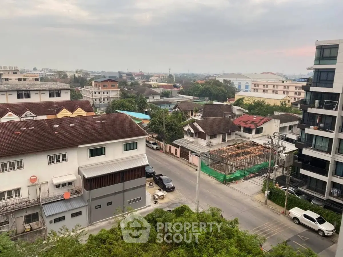 Scenic urban view from a high-rise balcony showcasing residential buildings and lush greenery.