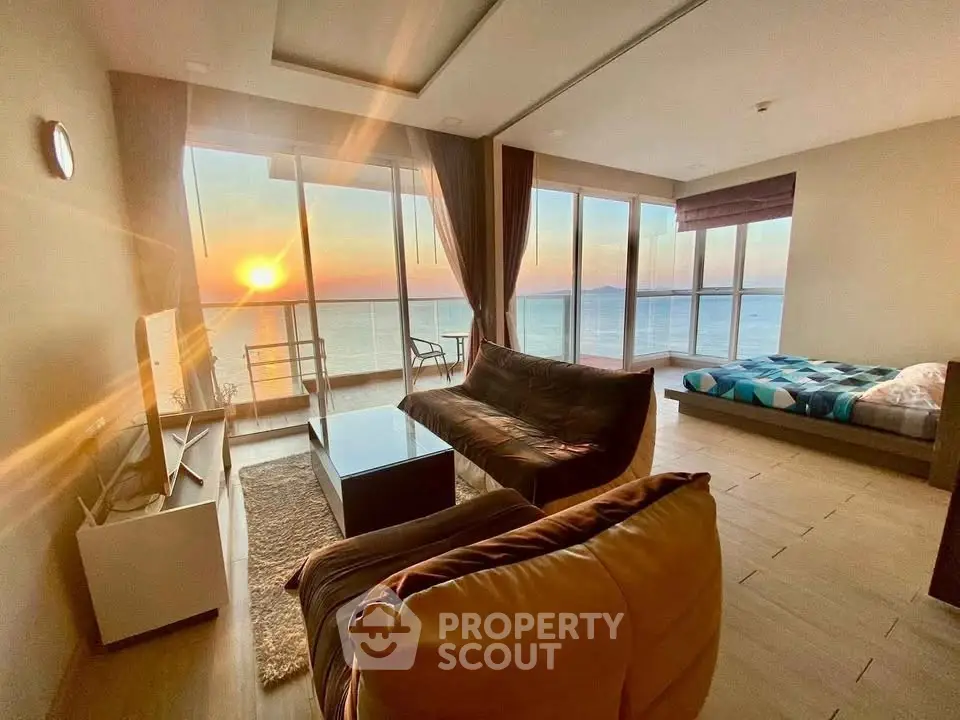 Stunning living room with ocean view and sunset, featuring cozy seating and modern decor.