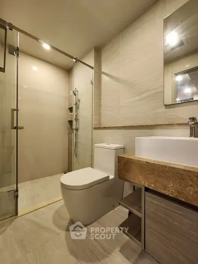 Modern bathroom with glass shower and elegant fixtures in a contemporary apartment.