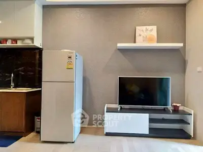 Modern living room with sleek TV setup and compact kitchen area.