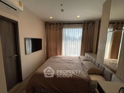 Cozy bedroom with modern decor, featuring a wall-mounted TV and large window with curtains.