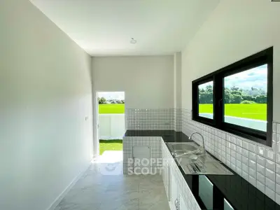 Bright kitchen with sleek black countertops and scenic green view.
