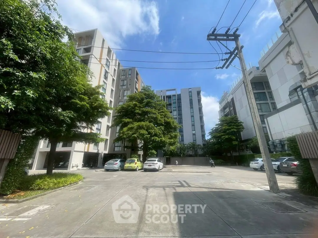 Modern apartment complex with spacious parking area and lush greenery.