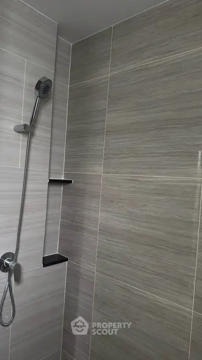Modern bathroom shower area with sleek gray tiles and chrome fixtures.
