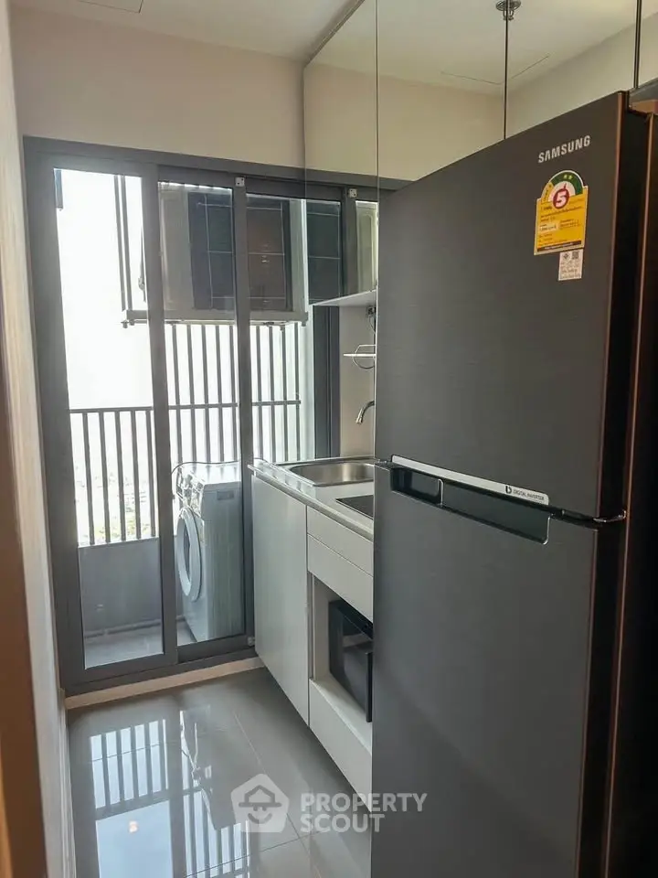 Modern kitchen with sleek appliances and balcony view, featuring a Samsung fridge and washing machine.